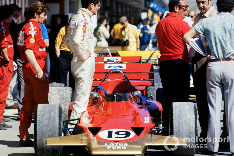 John Miles stands beside his Lotus 72 Ford in the pit lane