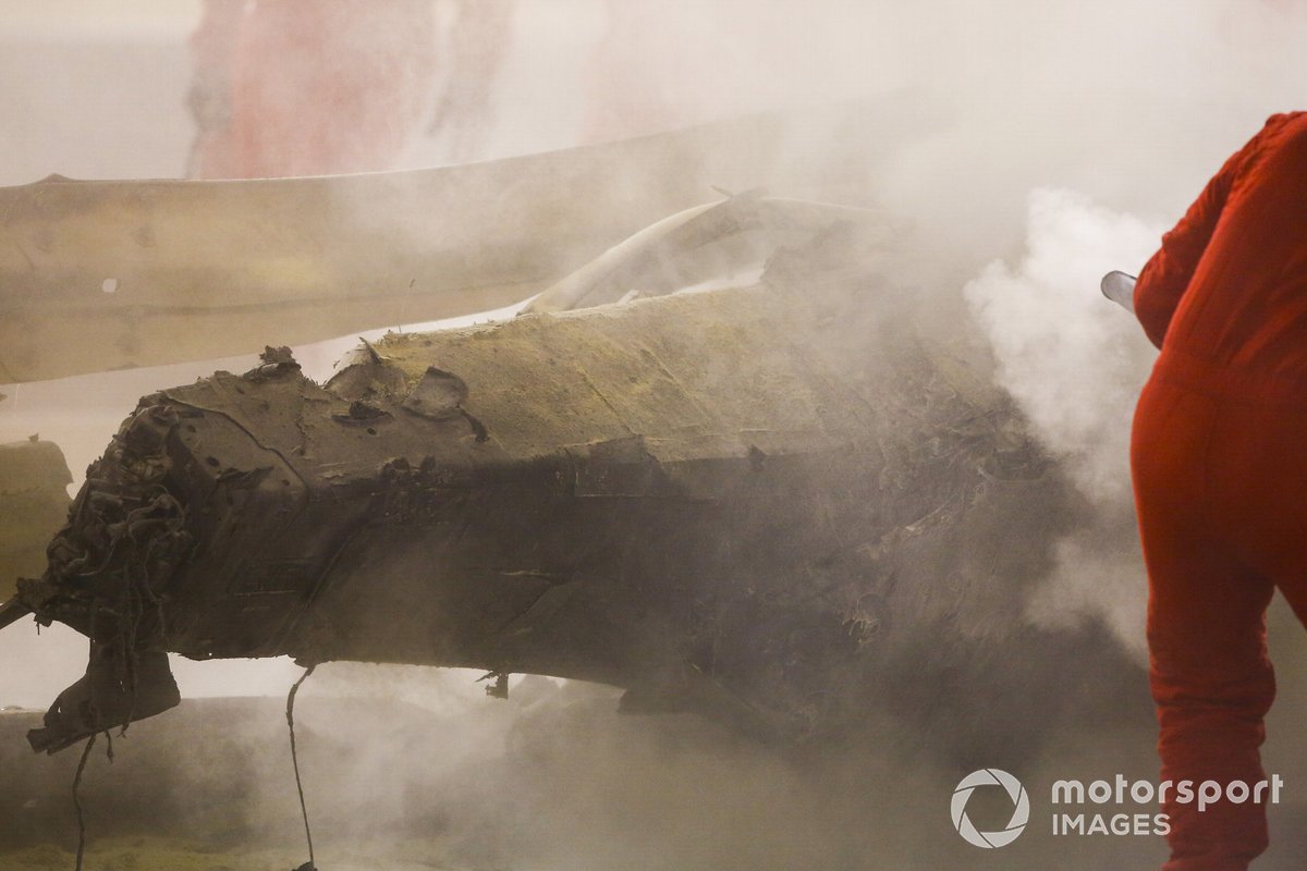 Fire marshals deal with the remains of the car of Romain Grosjean, Haas VF-20, in the Armco after a huge first lap crash