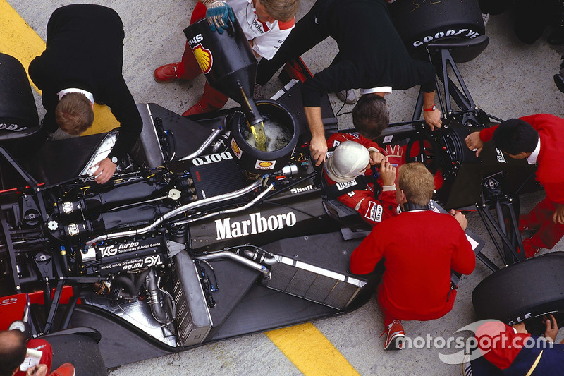 Alain Prost sits in his McLaren MP4/3 TAG Porsche while the mechanics get to work on the car and ref