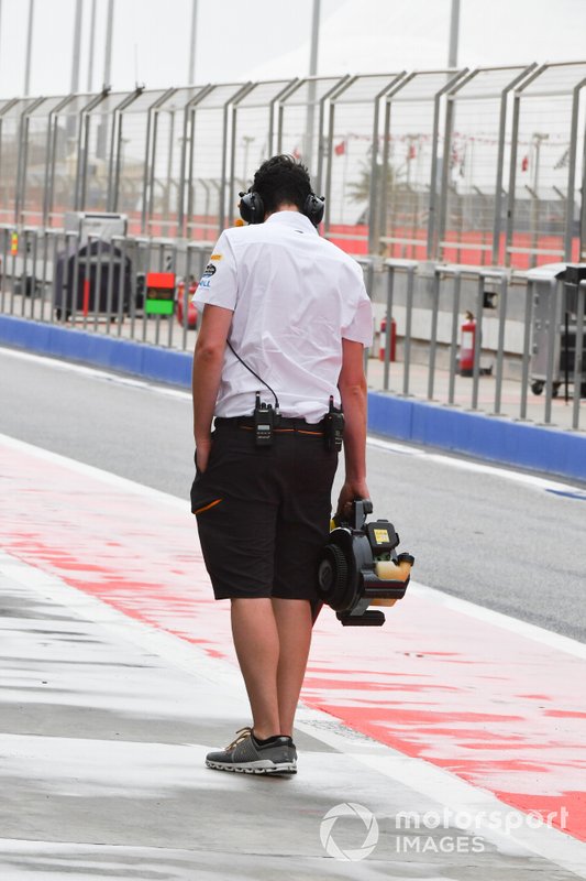 McLaren team member attempts to dry the pit lane