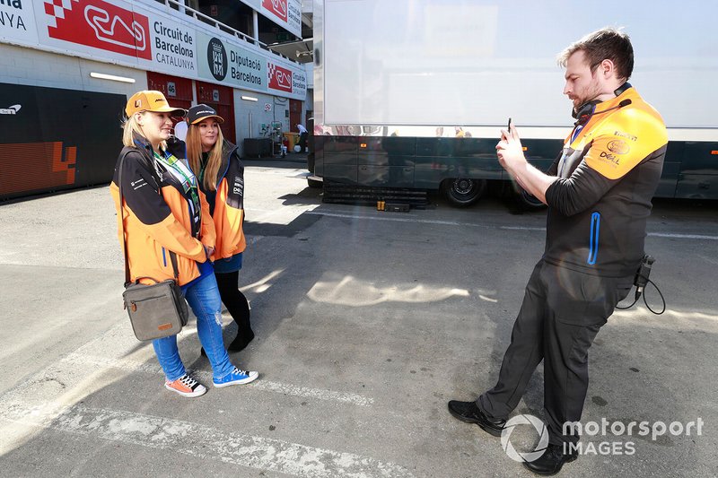 Un membro del team McLaren fa una foto a due fan