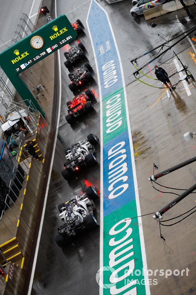 Pierre Gasly, AlphaTauri AT01, se encuentra en la parte trasera de una fila de coches en el pit lane, siendo Daniil Kvyat, AlphaTauri AT01 y un Ferrari