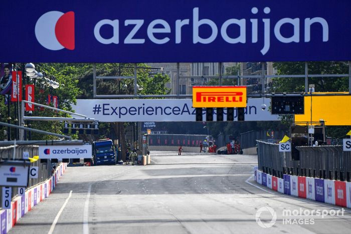 Los comisarios de pista asisten a Lance Stroll, Aston Martin AMR21, tras su accidente