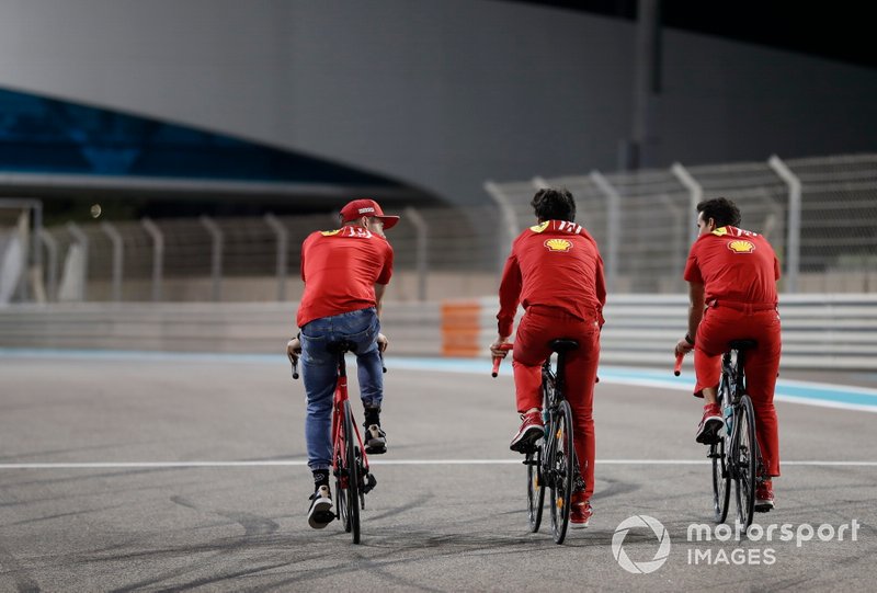 Charles Leclerc, Ferrari rides a push bike around the track with members of the errari team
