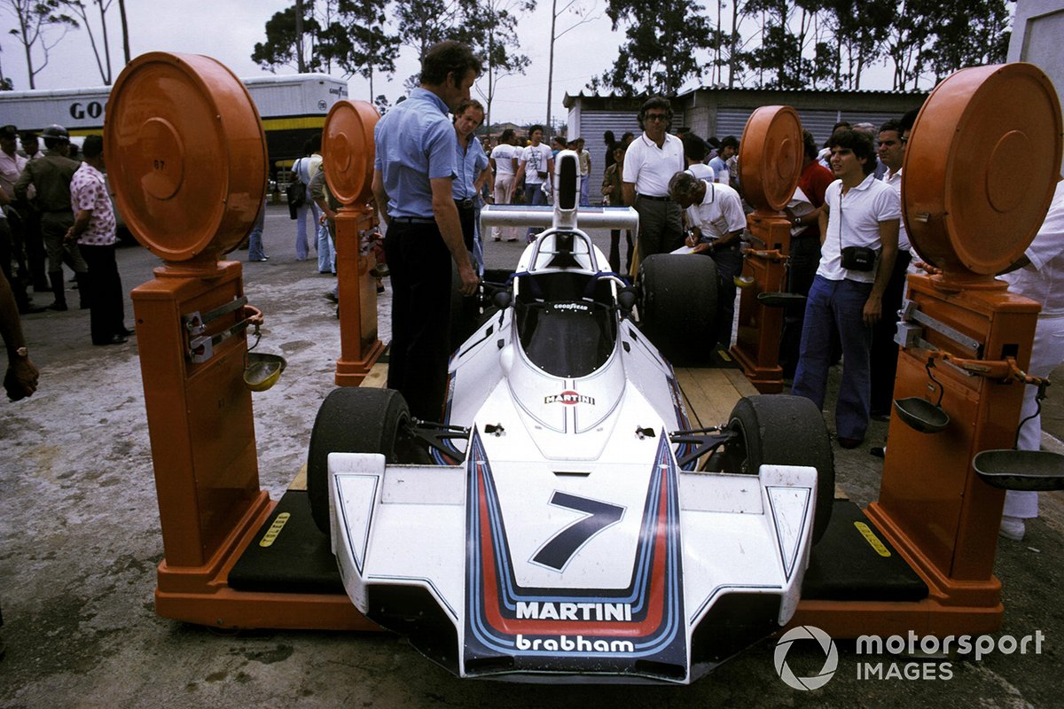 Un joven Nelson Piquet mira como el Brabham BT44B octavo lugar de Carlos Reutemann es pesado en el área del paddock