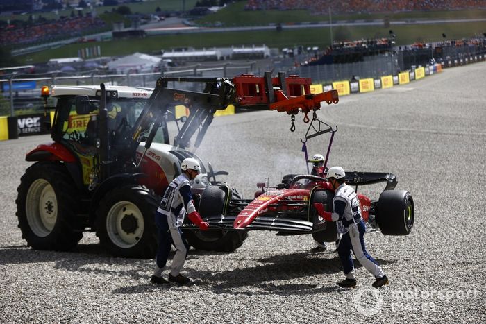 Los oficiales de pista retiran del circuito el coche incendiado de Carlos Sainz, el Ferrari F1-75