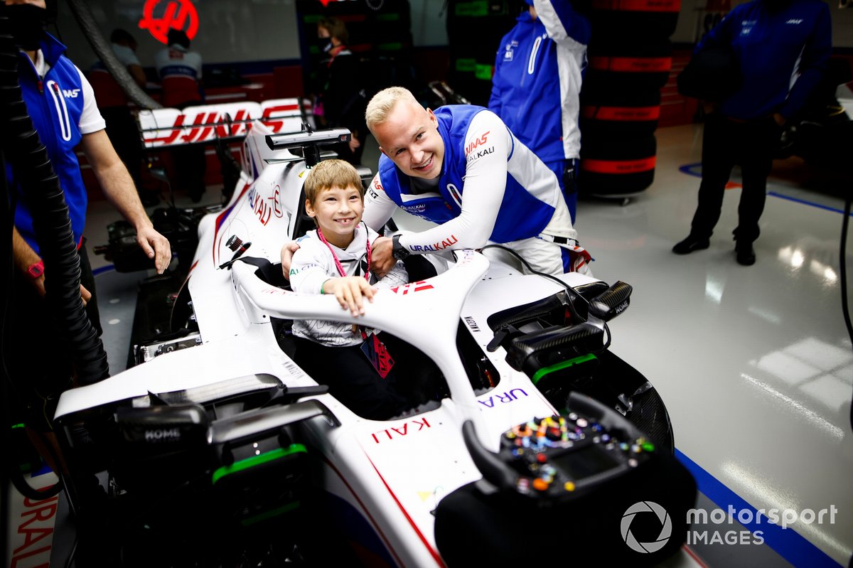 Nikita Mazepin, Haas F1, shows the cockpit of his car to a young guest