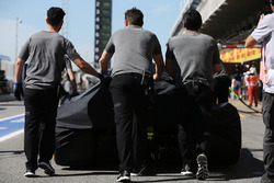 McLaren engineers move the car of Fernando Alonso, McLaren MCL32, in the pit lane, under covers