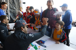 Fernando Alonso, McLaren, give a high-five to a young fan, as Stoffel Vandoorne, McLaren, signs autographs