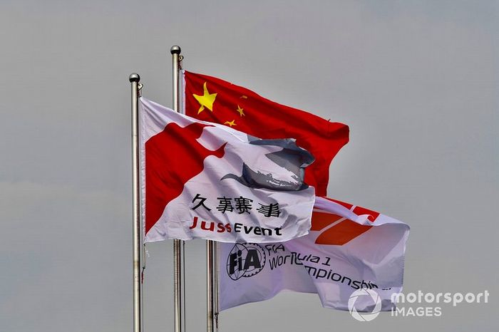 Una bandera china junto a una bandera de Fórmula 1 de la FIA y una bandera de evento de Juss.