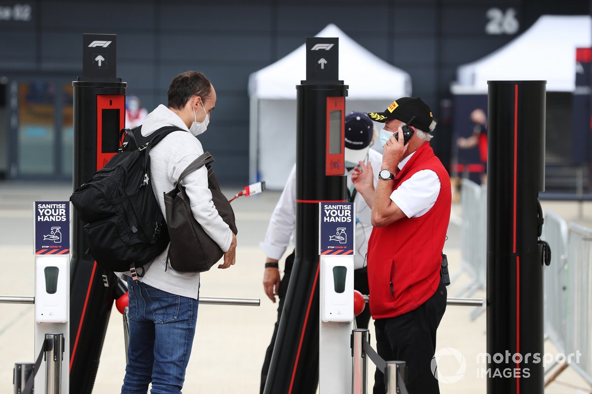 Robert Kubica, Alfa Romeo, muestra su pase a la entrada al paddock