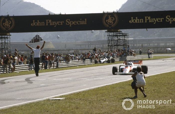 Alain Prost, McLaren MP4-2 TAG, takes the chequered flag