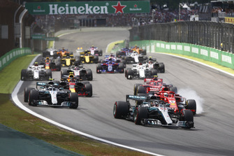 Lewis Hamilton, Mercedes AMG F1 W09, leads a locked-up Sebastian Vettel, Ferrari SF71H, Valtteri Bottas, Mercedes AMG F1 W09, Kimi Raikkonen, Ferrari SF71H, Max Verstappen, Red Bull Racing RB14 Tag Heuer, and the rest of the field at the start.