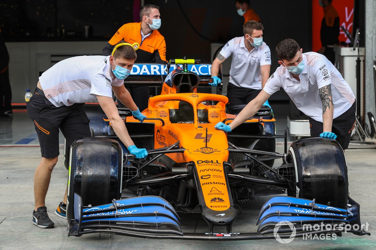 McLaren personnel wheel a car out of the garage