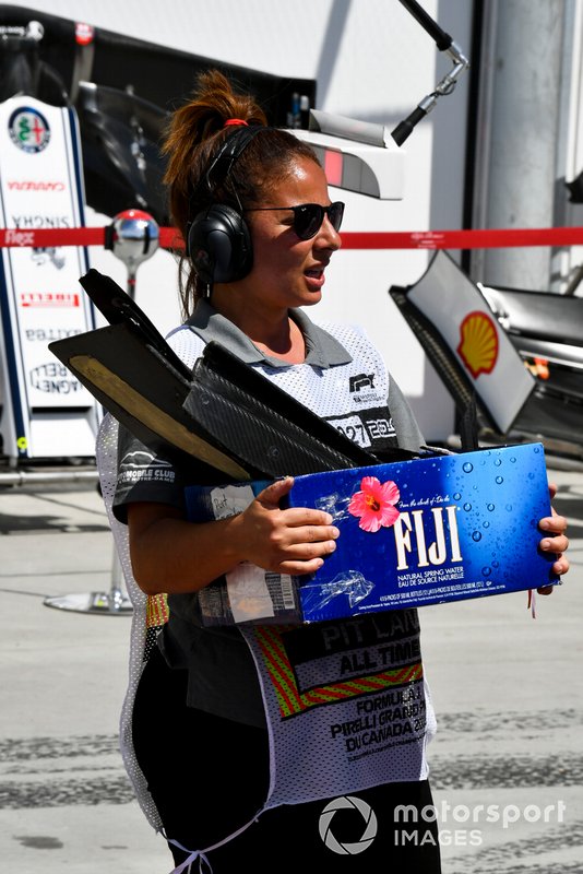 Una marshal riporta ai box una scatola di pezzi della monoposto incidentata Kevin Magnussen, Haas VF-19