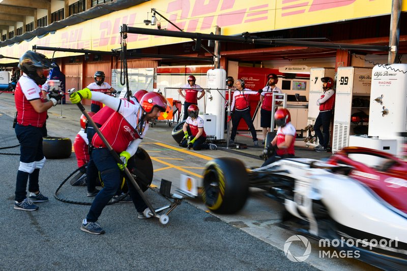 An Alfa Romeo Racing C38 is serviced by mechanics during a practice pit stop