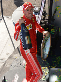 El ganador de la carrera, Sebastian Vettel, Ferrari, celebra ene l podio con el trofeo y champagne