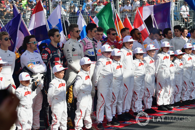 Drivers and grid kids observe the National Anthem on the grid