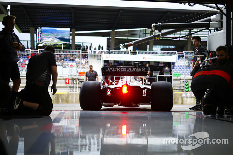 I meccanici Haas guardano Kevin Magnussen, Haas F1 Team VF-18, uscire dal garage del team