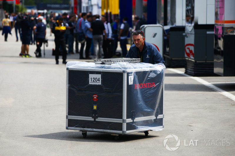 A Honda team member pushes an engine crate in the paddock