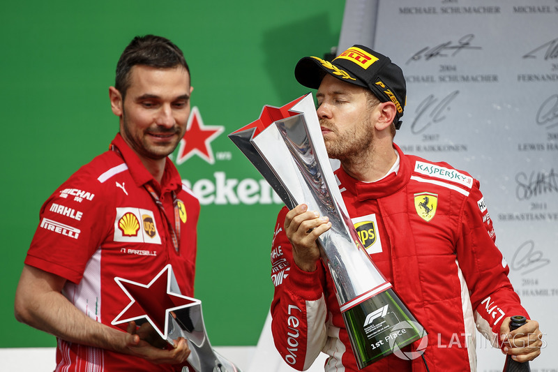 Sebastian Vettel, Ferrari, 1st position, kisses his trophy on the podium alongside Nicola Bariselli,
