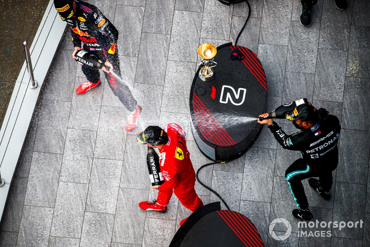 Carlos Sainz Jr., Ferrari, 3a posizione, Max Verstappen, Red Bull Racing, 2a posizione, e Lewis Hamilton, Mercedes, 1a posizione, spruzzano Champagne sul podio
