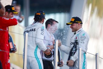 Winner Lewis Hamilton, Mercedes AMG F1, and Valtteri Bottas, Mercedes AMG F1, spray champagne on the podium. Charles Leclerc, Ferrari, looks on