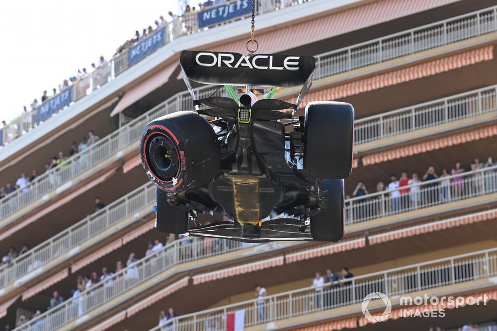 Oficiales de pista retiran el coche dañado de Sergio Pérez, Red Bull Racing RB19, del circuito tras un accidente en la Q1