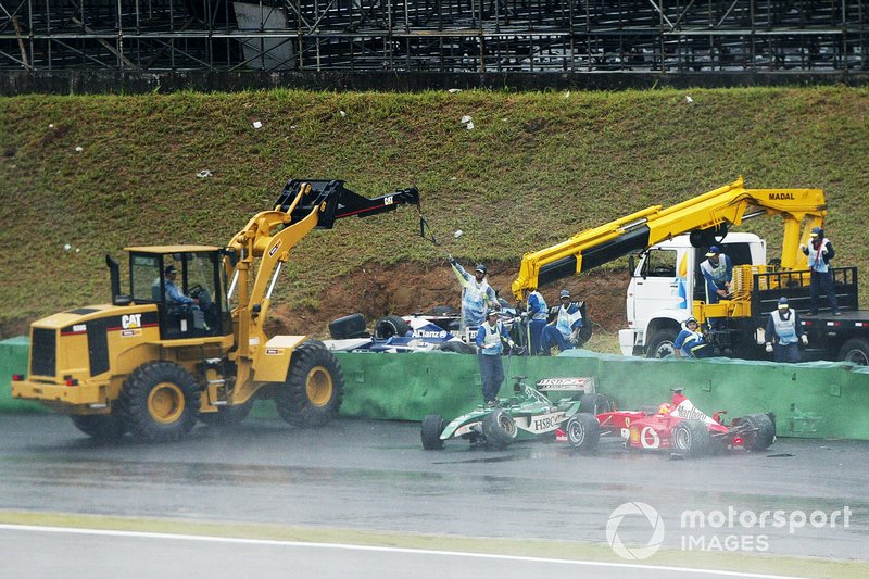 Michael Schumacher, Ferrari F2002, esce alla Curva do Sol rischiando di centrare la monoposto di Antonio Pizzonia, che i marshal stanno rimuovendo dal circuito