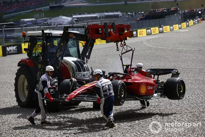 Los oficiales de pista retiran el coche incendiado de Carlos Sainz, Ferrari F1-75