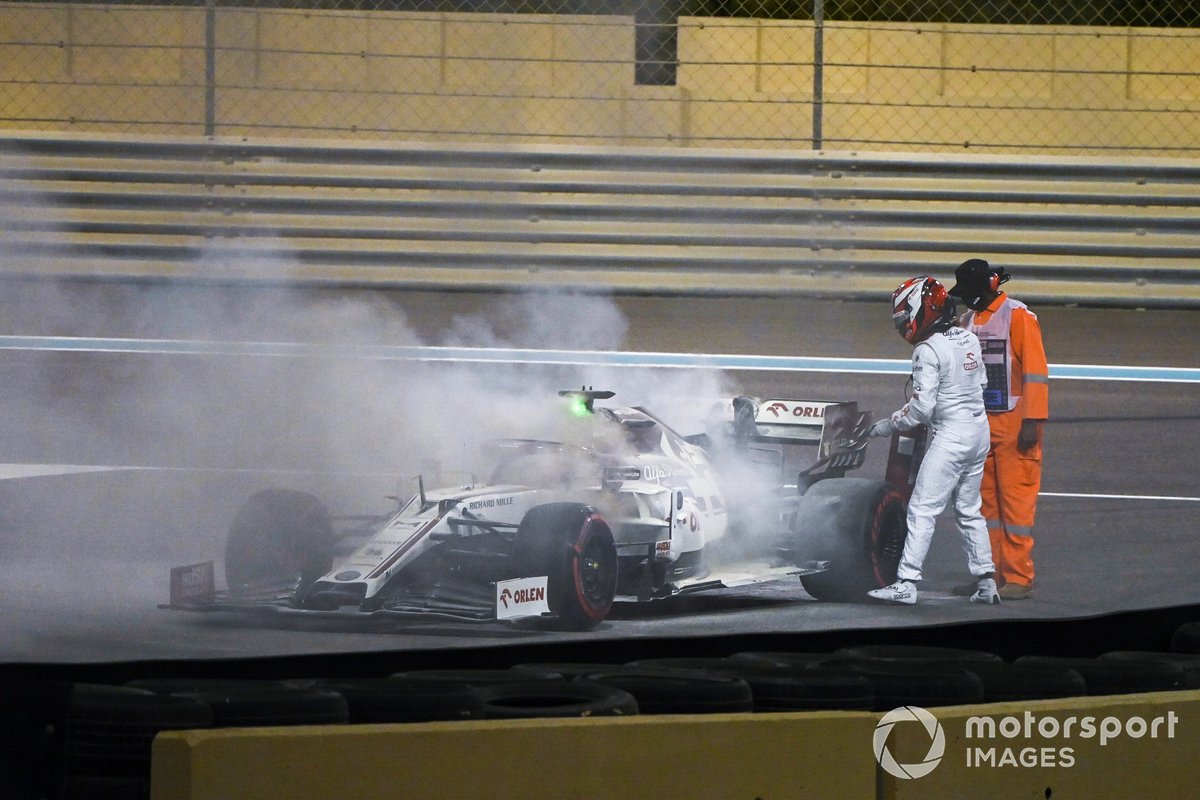 Kimi Raikkonen, Alfa Romeo Racing C39, assists a marshal in extinguishing a fire in his car