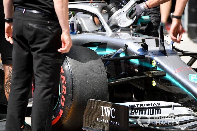 Les mécaniciens Mercedes regardent un pneu de Valtteri Bottas, Mercedes AMG W10 aux qualifications