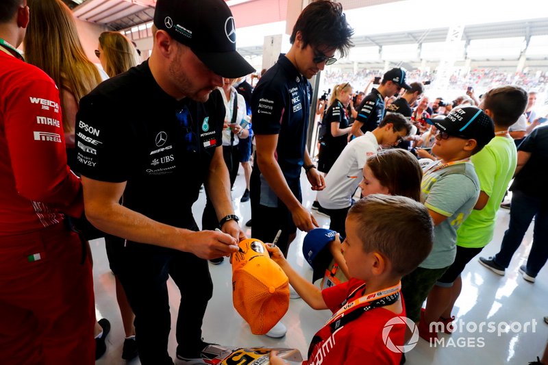 Valtteri Bottas, Mercedes AMG F1, and Lance Stroll, Racing Point, sign autographs for young fans
