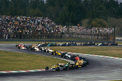 Nigel Mansell, Williams FW11B Honda, leads Teo Fabi, Benetton B187 Ford, Ayrton Senna, Lotus 99T Honda, and the rest of the field on the first lap