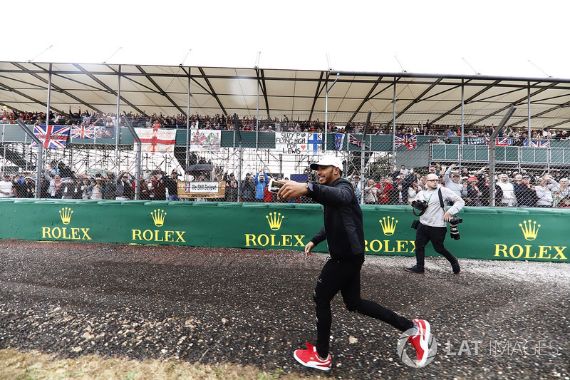 Lewis Hamilton, Mercedes AMG F1, runs past fans in a grandstand while filming them on his phone