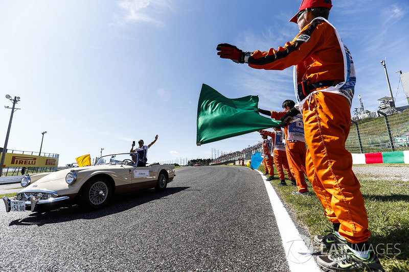 Oficiales de pista ven a Felipe Massa, Williams,pasar en el desfile de pilotos