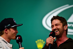 (L to R): Nico Rosberg, Mercedes AMG F1 on the podium with Gerard Butler, Actor