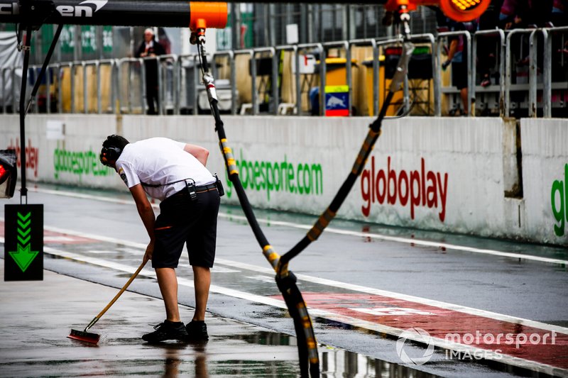 A McLaren mechanic swaps water from outside the garage