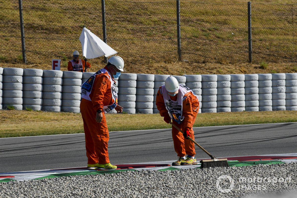 Los oficiales de pista barren la grava