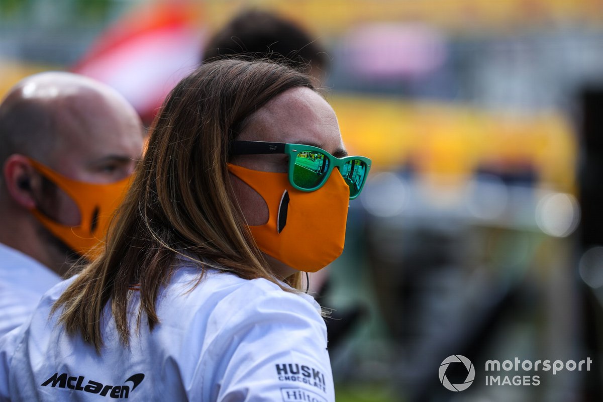A McLaren team member wears a mask on the grid