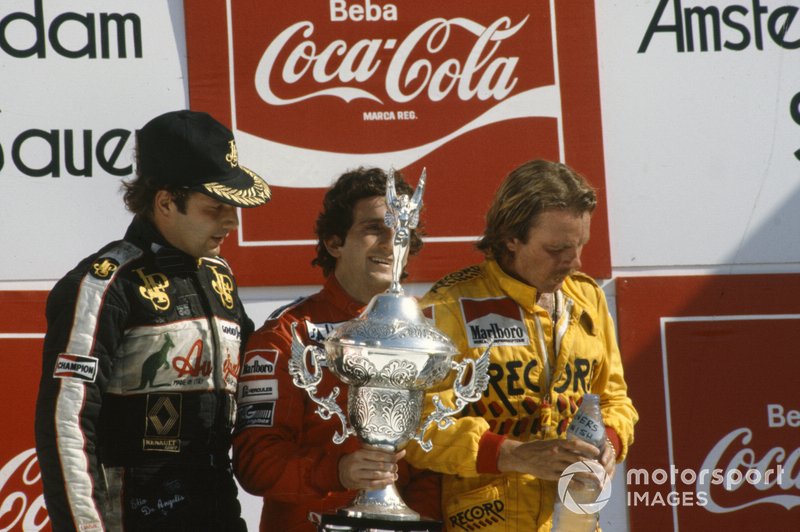 Alain Prost, 1st position, holds his trophy alongside Keke Rosberg, 2nd position, and Elio de Angelis, 3rd position