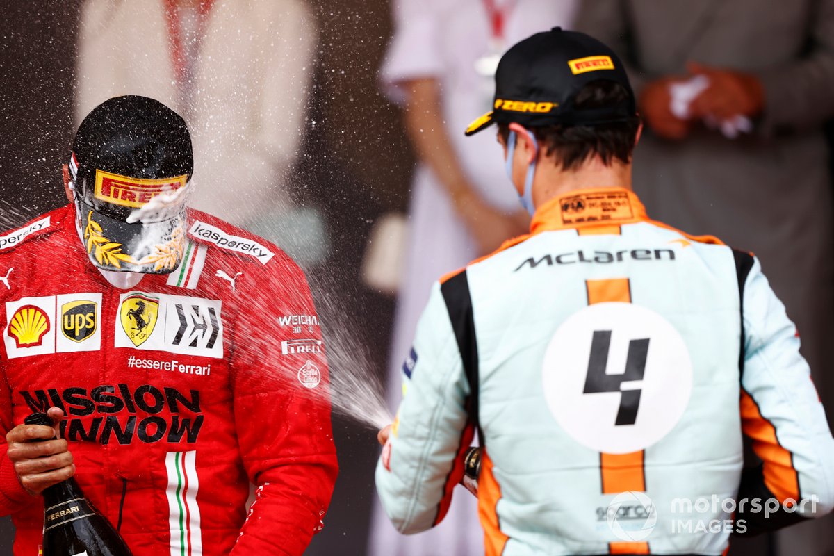 Carlos Sainz Jr., Ferrari, secondo classificato, e Lando Norris, McLaren, terzo classificato, spruzza Champagne sul podio