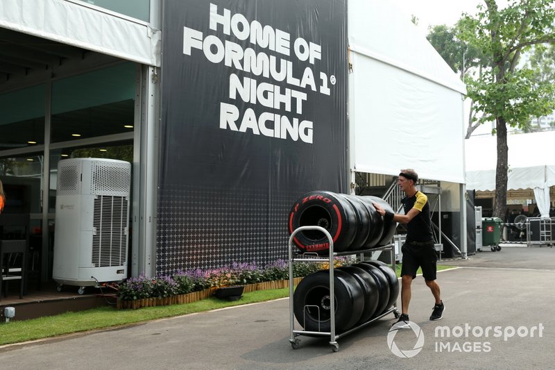 A Renault team member pushes Pirelli tyres on a trolley in the paddock