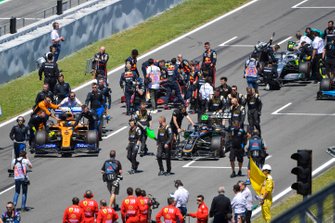 Lando Norris, McLaren MCL34, en Romain Grosjean, Haas F1 Team VF-19, arriveren op de grid