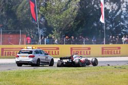 An official car stops next to the damaged Romain Grosjean Haas F1 Team VF-18