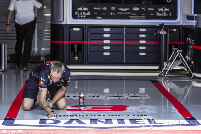 Un mécanicien de Red Bull Racing nettoie le sol du garage
