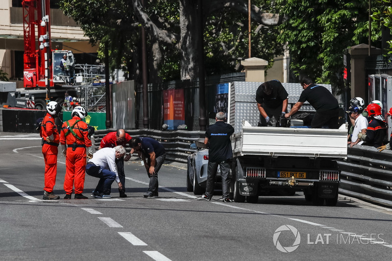 Charlie Whiting, delegado de la FIA supervisa las reparaciones de una cubierta de desagüe suelta que provocó que el FP2 se marcara con una bandera roja
