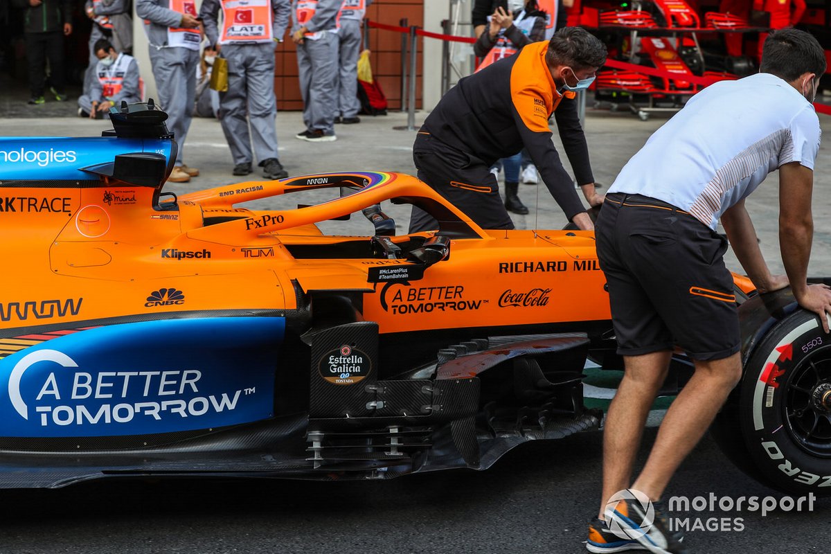 McLaren personnel wheel a car along the pitlane