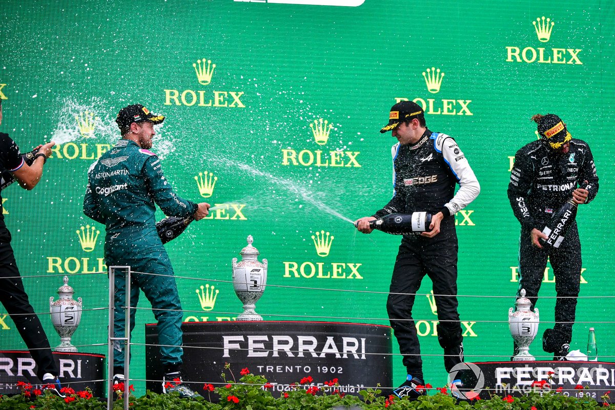 Sebastian Vettel, Aston Martin, secondo classificato, Esteban Ocon, Alpine F1, primo classificato, e Lewis Hamilton, Mercedes, terzo classificato, spruzzano Champagne sul podio