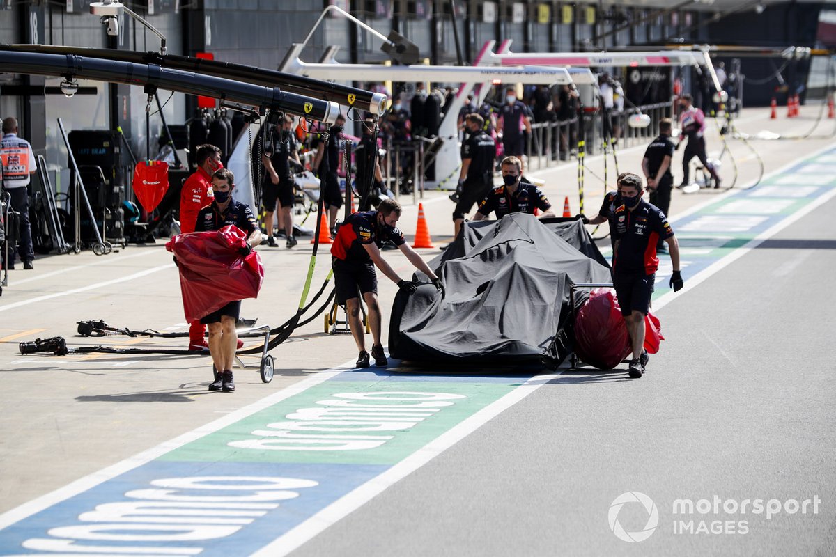 Red Bull mechanics return the damaged car of Alex Albon, Red Bull Racing RB16, to the garage under a tarpaulin, after his crash in FP2